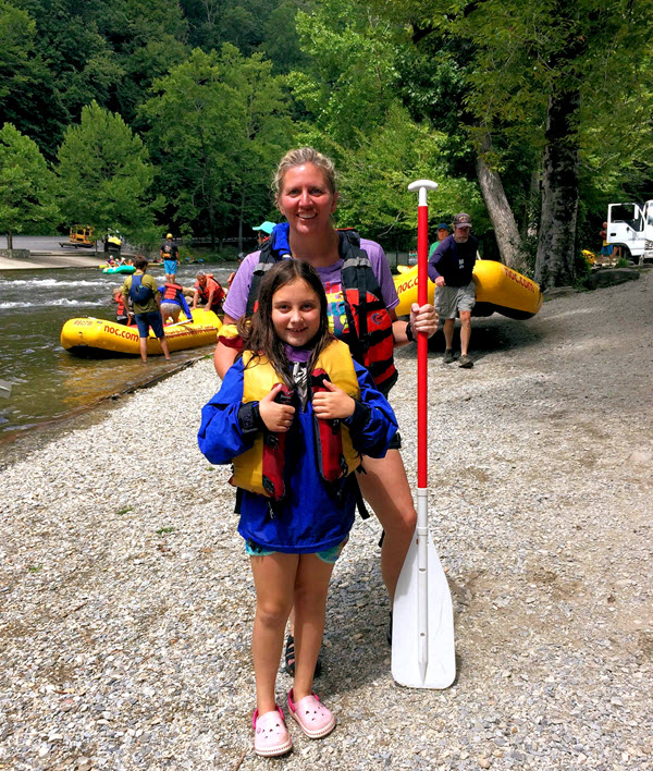 A mother and daughter stand on the bank of the Nantahala after rafting