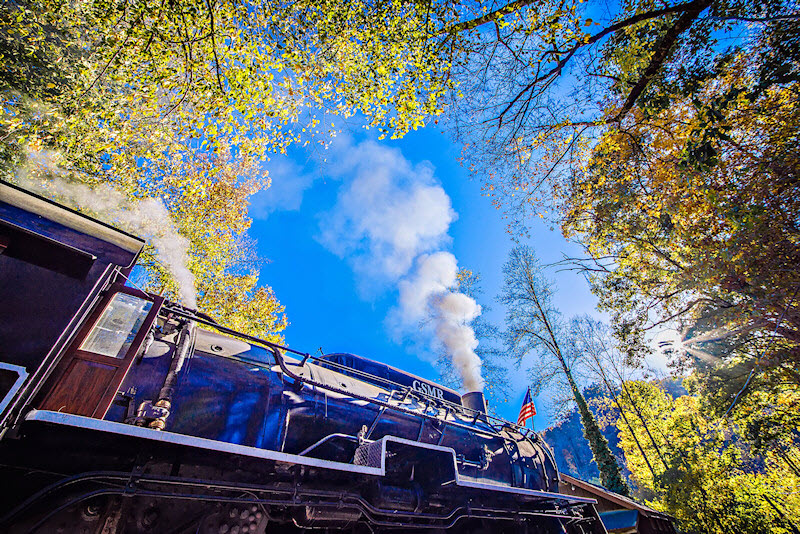 Great Smoky Mountain Railroad steam engine enters a clearing in the mountains