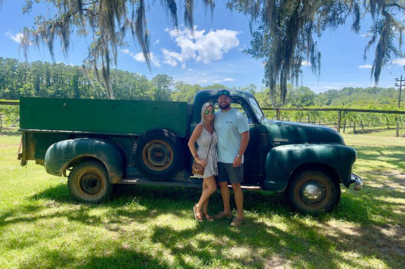 Couple poses at a vineyard in front of an old pickup truck