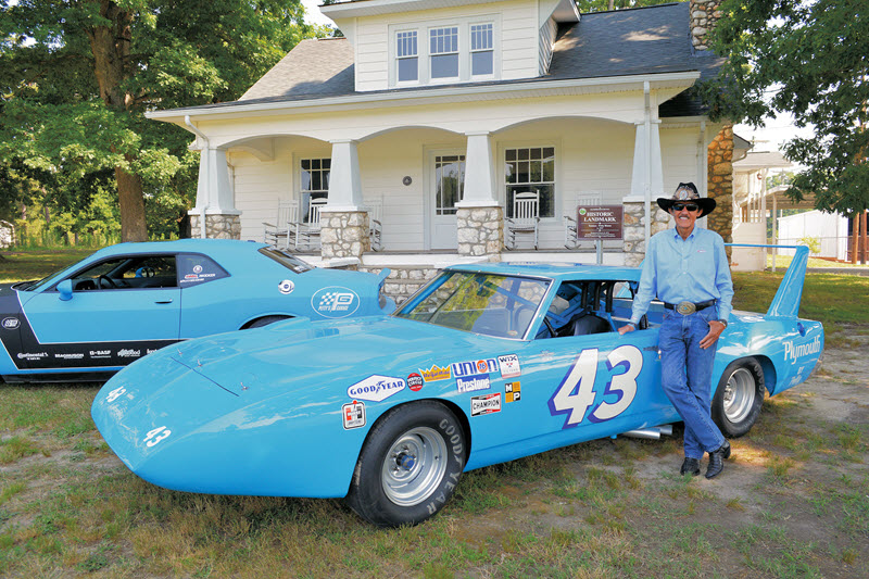 NASCAR driver Richard Petty stands beside a blue race car at the Petty Museum