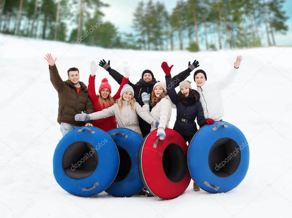 group of smiling friends with snow tubes