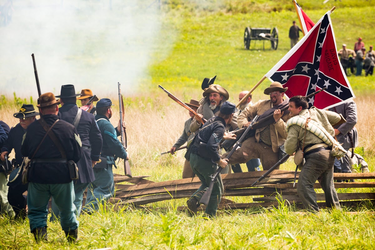 Civil War reenactors recount Confederate troops leaping a fence in an attack upon a Union force
