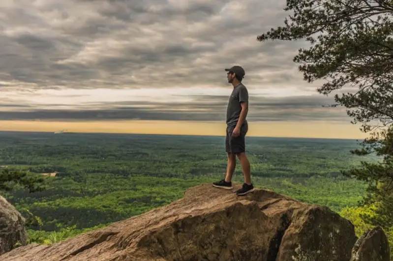 Guy standing at the peak of Crowders Mountain