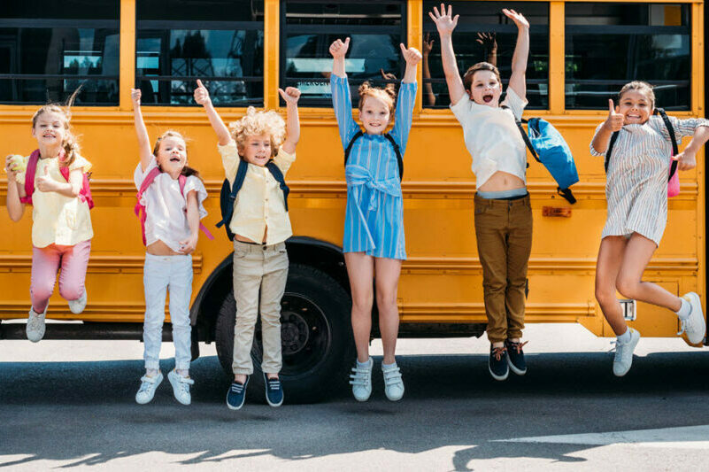 School children on a field trip in front of a yellow school bus