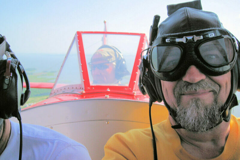 a man riding in the front seat of a biplane