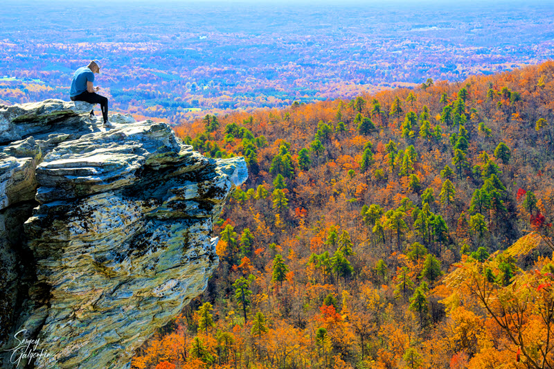 Man sits atop Hanging Rock overlooking the Piedmont region