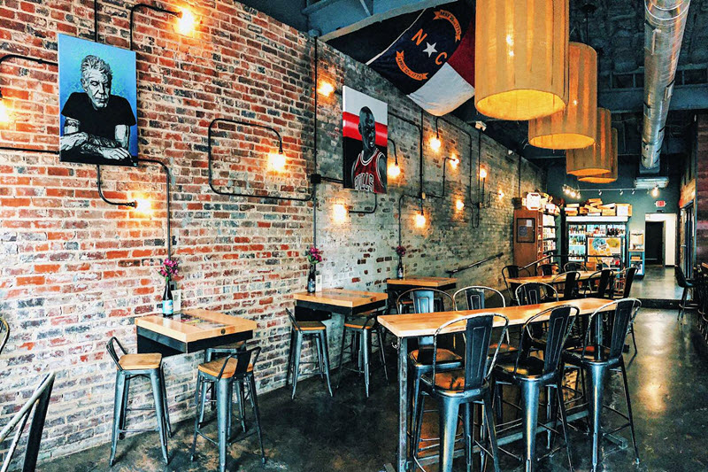 high top tables and chairs line an old brick wall at Summit Beer Shop