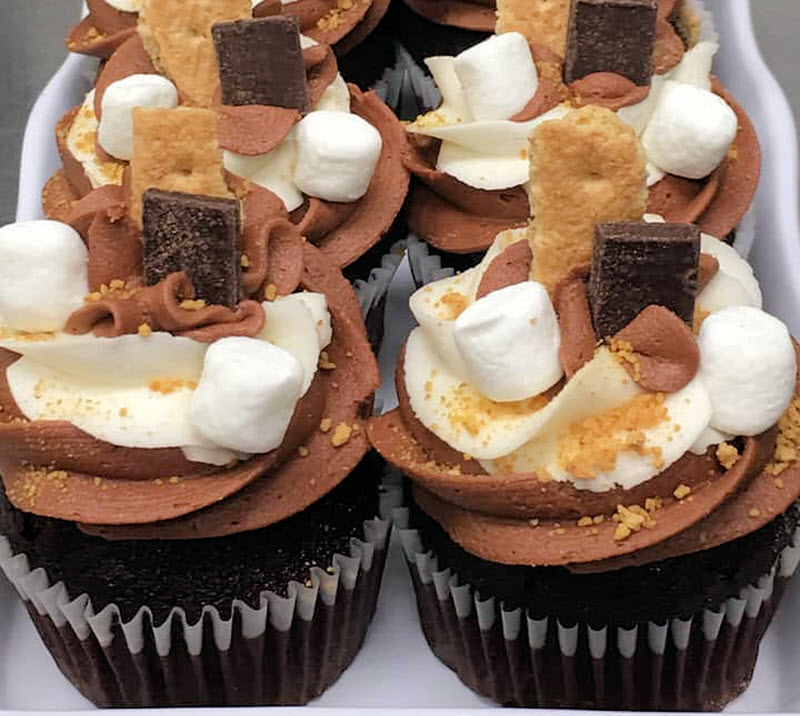 Cupcakes with marshmallows, chocolate, and graham cracker line the tray