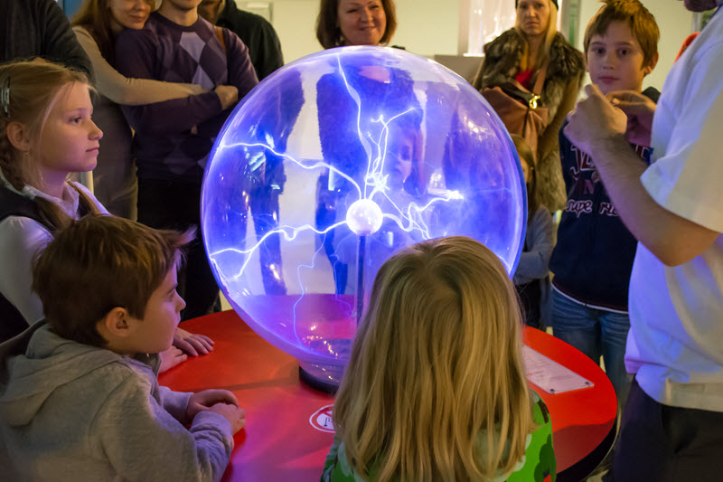 Students on a field trip to a science museum gaze at a plasma ball.
