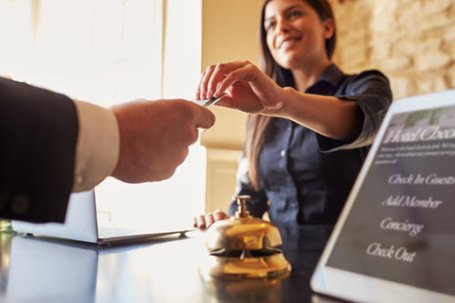Hotel front desk checks in guest who found cheap hotel rates