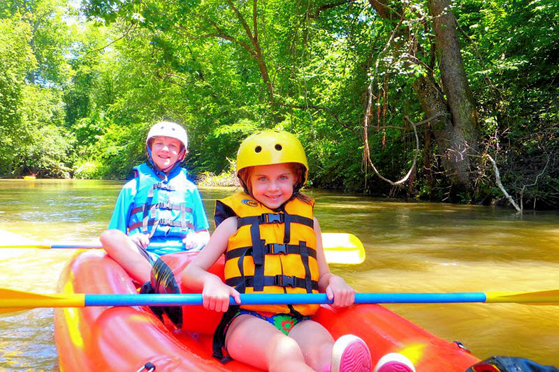 Two kids paddle a kayak on a Green River Adventures tour.