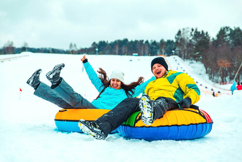 Two young people snow tubing
