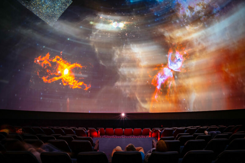 Two people watching a galaxy display at a planetarium