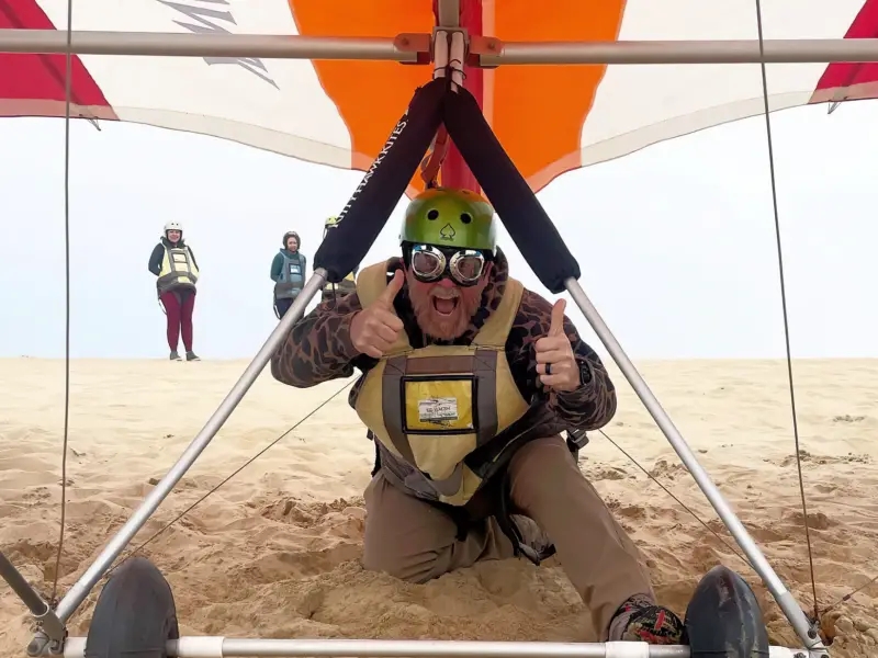 Guy giving the thumbs up sign before starting a hang gliding flight