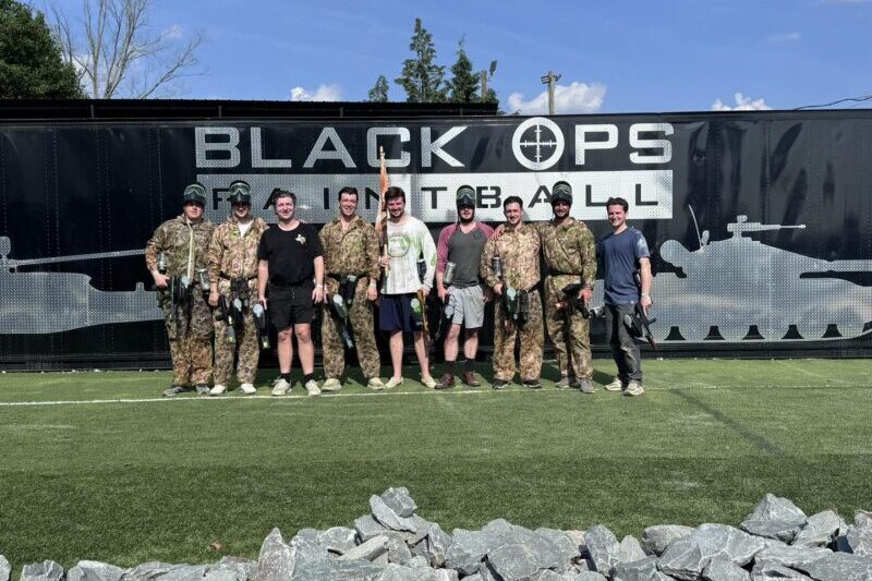 Guys standing in front of a Black Ops paintball banner