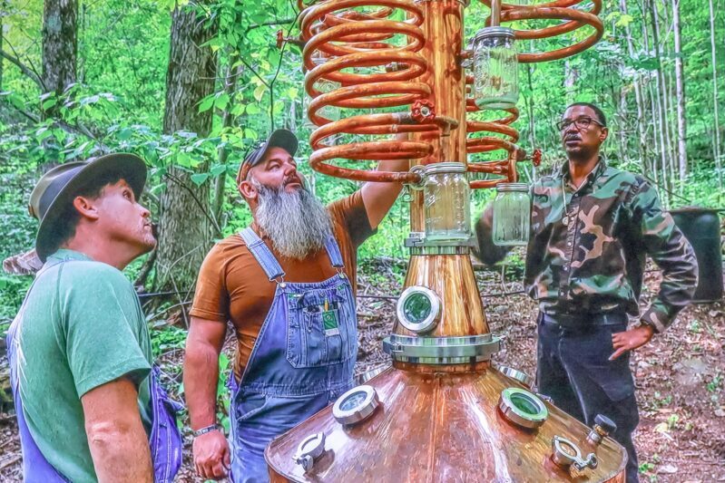 3 men observing a moonshine still at the Hillbilly Jam