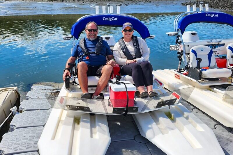 A couple posing on a Creek Cat at the dock