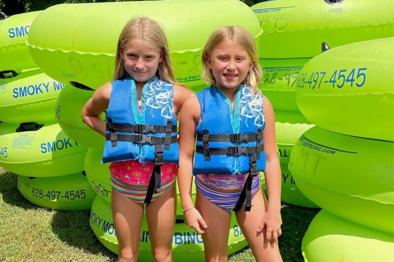 Siblings posing in front of river tube stacks